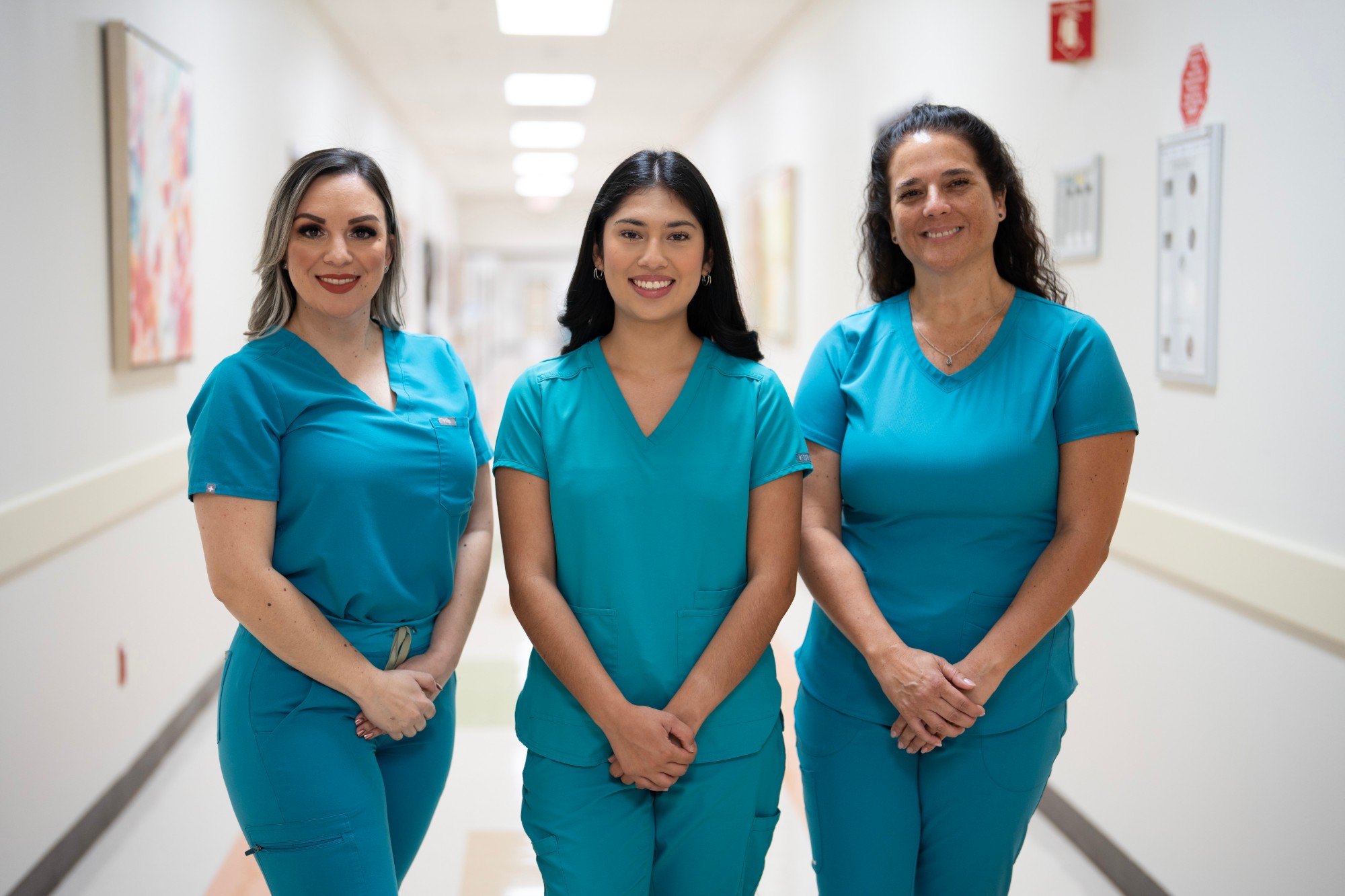 Three healthcare staff in scrubs in an Edinburg medical facility hallway